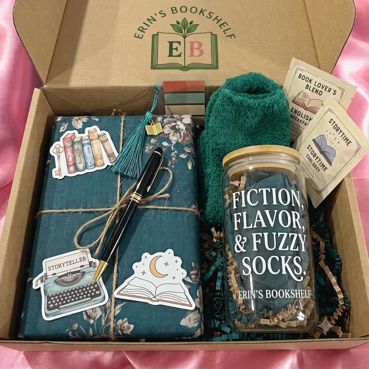 Erin's Monthly Club box with a wrapped book, tabs, tea, fuzzy socks, a pen, stickers, and a bookish tumbler